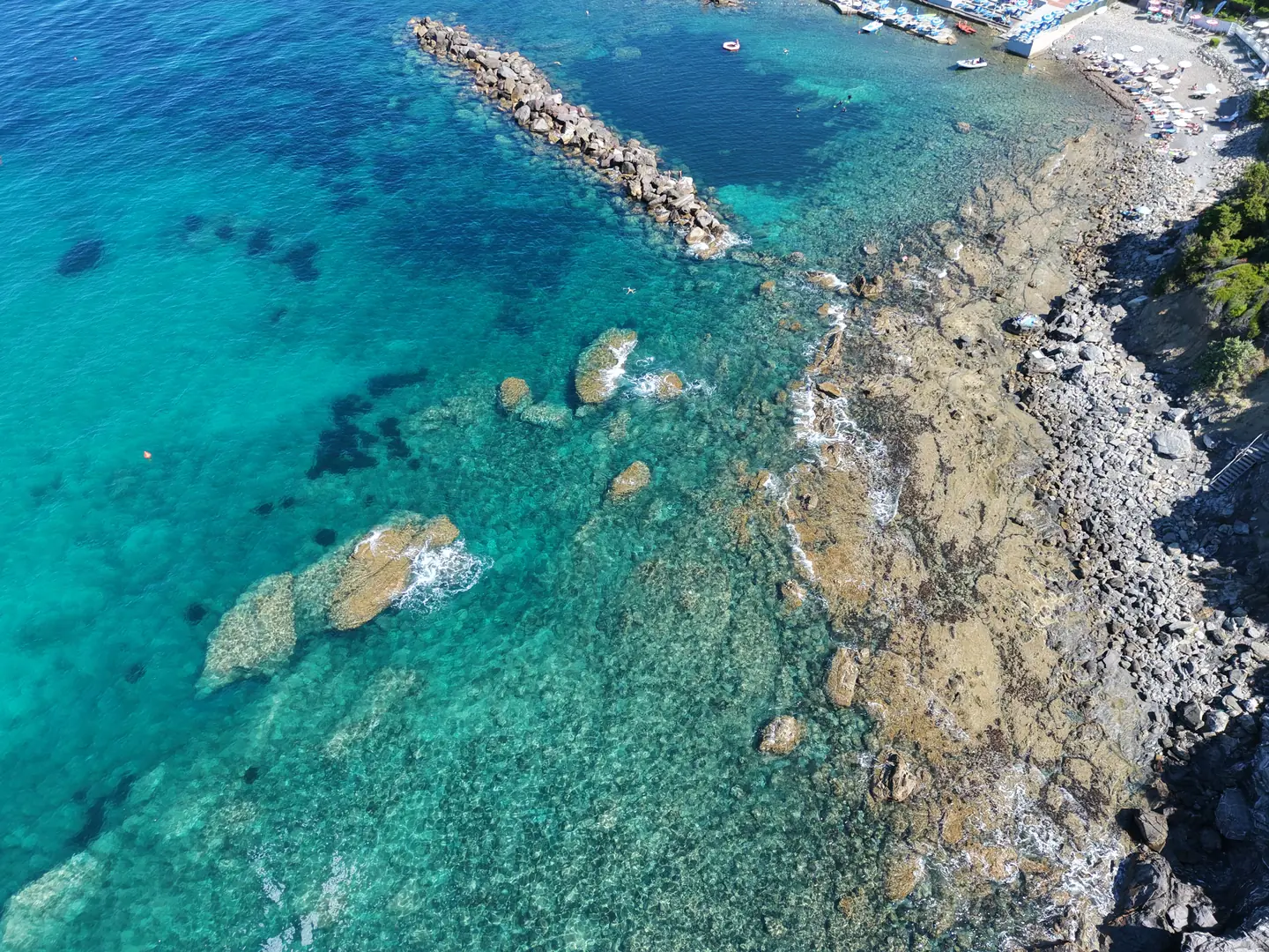 Fondale bianco e acqua trasparente visti dal drone in verticale, scogliera livornese