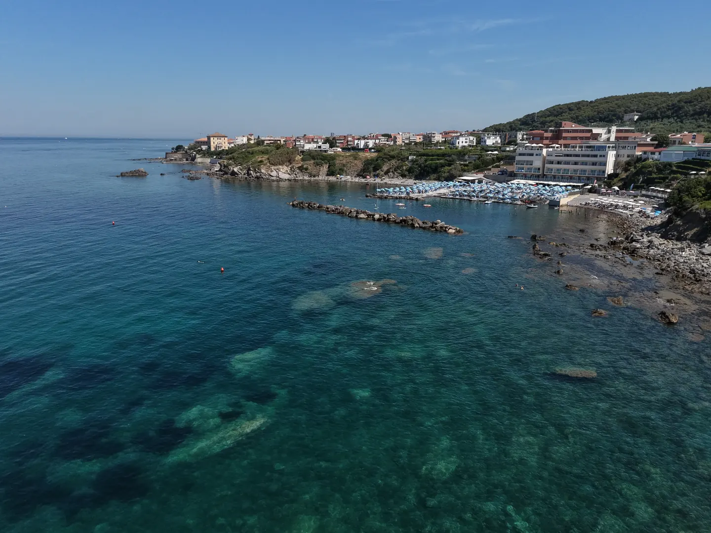 Baia di Quercianella vista dal drone: punta rocciosa, colline verdi e mare limpido, costa toscana