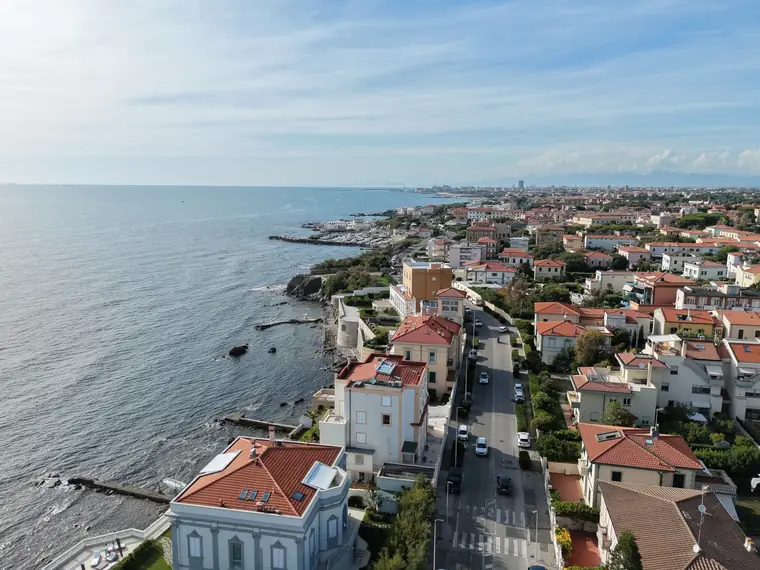 Borgo costiero in piena luce con scogliera e mare, foto aerea
