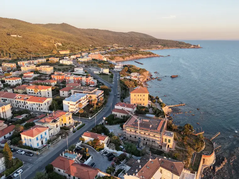 Case sul mare all'ora d'oro con colline alle spalle, foto aerea