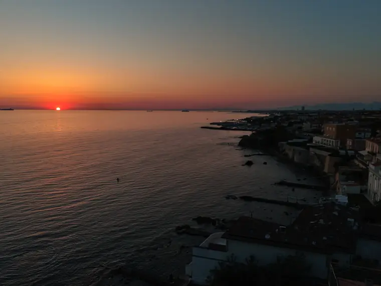 Sole rosso che tocca l'orizzonte sul mare scuro, foto aerea