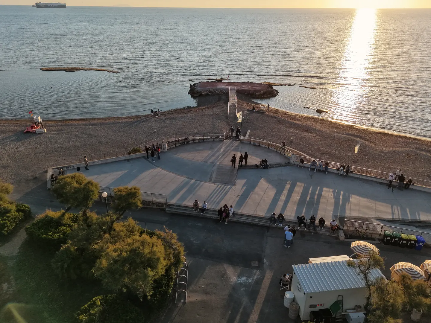 Tramonto al Baretto dei Tre Ponti a Livorno: la terrazza rotonda sul mare con la passerella verso lo scoglio, vista dal drone